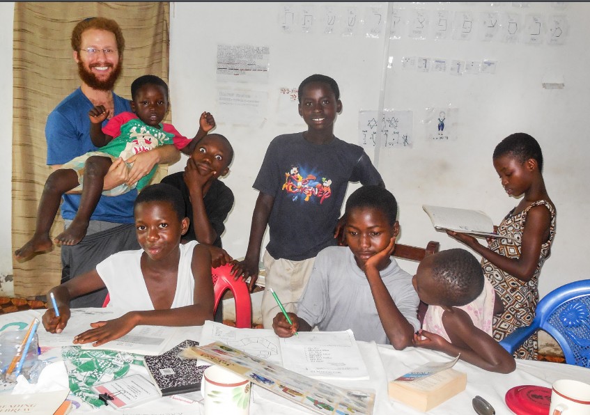 Loren Berman, Kulanu Teaching Fellow, with the elementary and middle school children in Sefwi Wiawso, Ghana, taking a break while practicing the Aleph-Bet