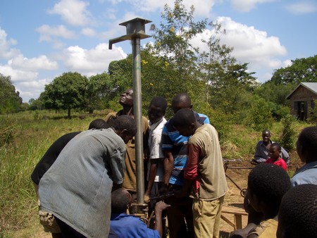 Villagers get water from the repaired borehole (Photo by Yoash Mayende)